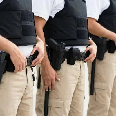 Guardias Armados alineados con las manos en el uniforme, mostrando una postura firme y de vigilancia.